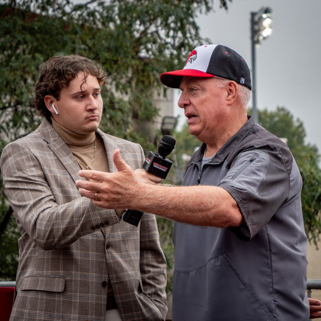 Student interviewing subject at homecoming game.