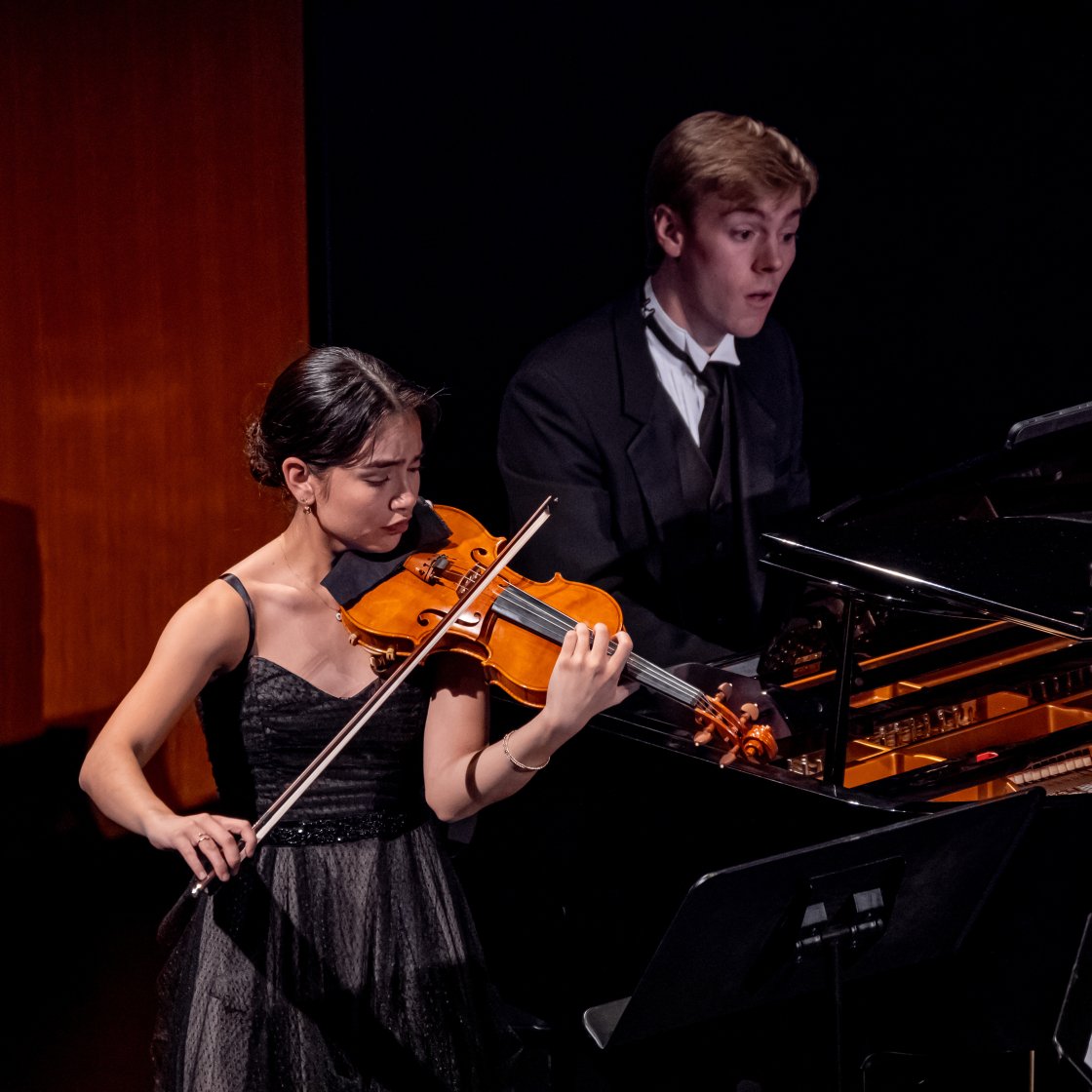 Violinist performing on stage for recital with pianist