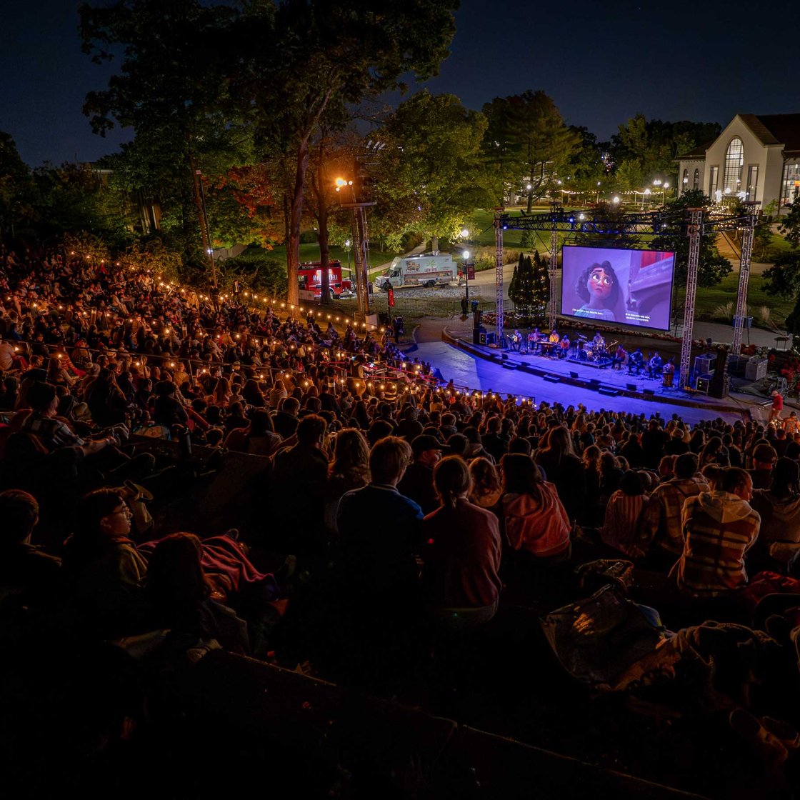 People sitting in an outdoor theater for a live music performance.