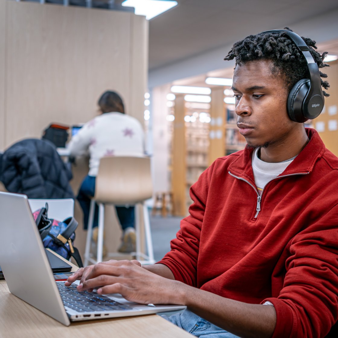 student wearing headphones doing work on laptop
