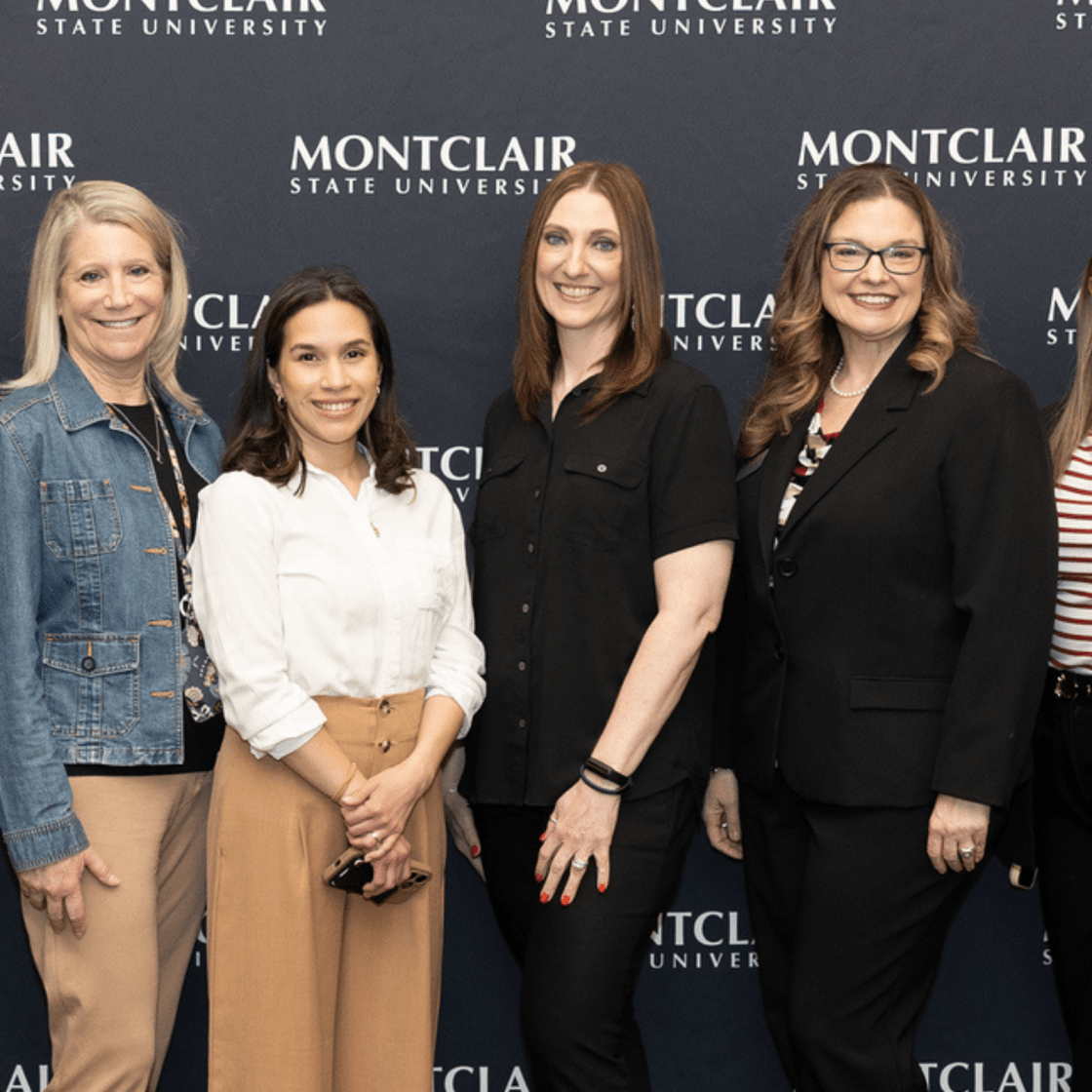 Student Success Team pose in front of a step and repeat.