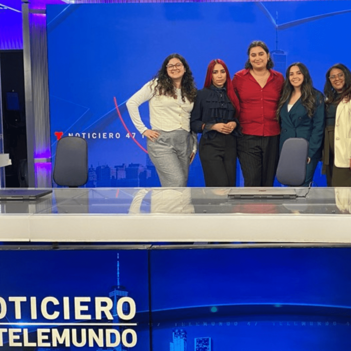 Students pose in front of an anchor desk on Telemundo 47 set.