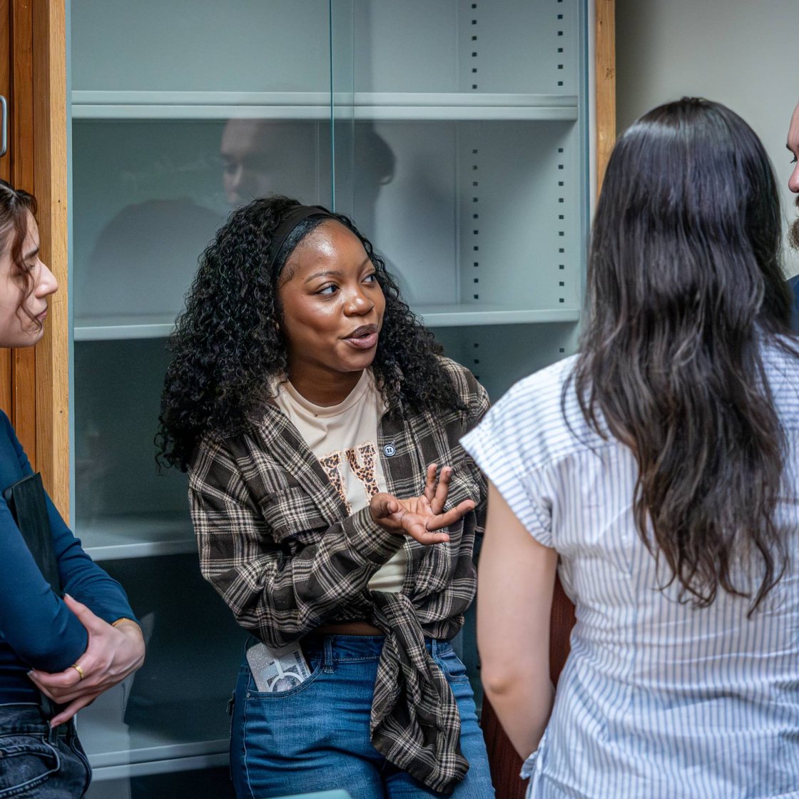 A group of college students talk together in a classroom