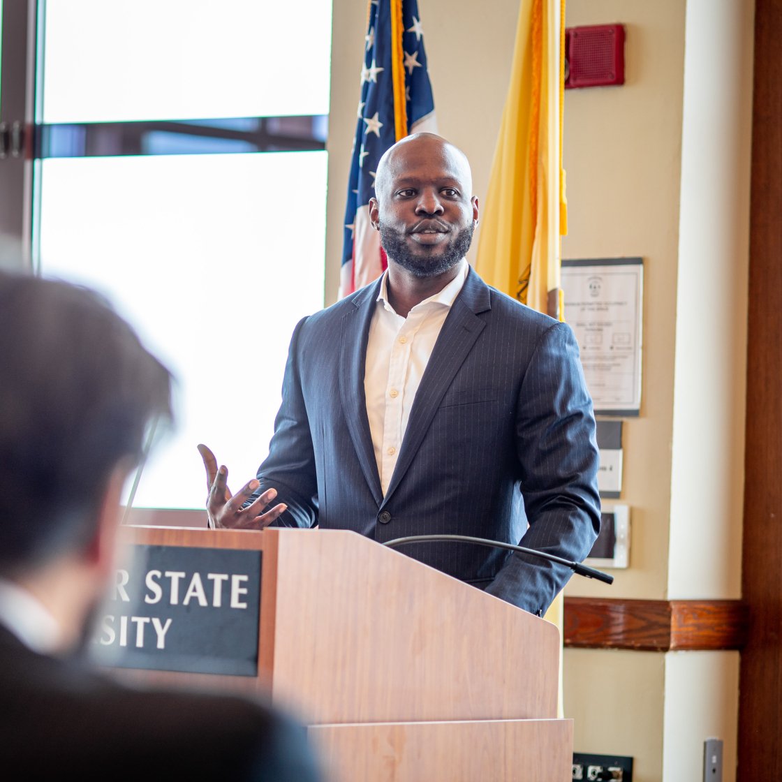 Speaker addresses seated attendees from a lectern.