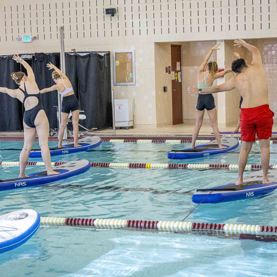 Students practice yoga on paddleboards at the Rec Center.