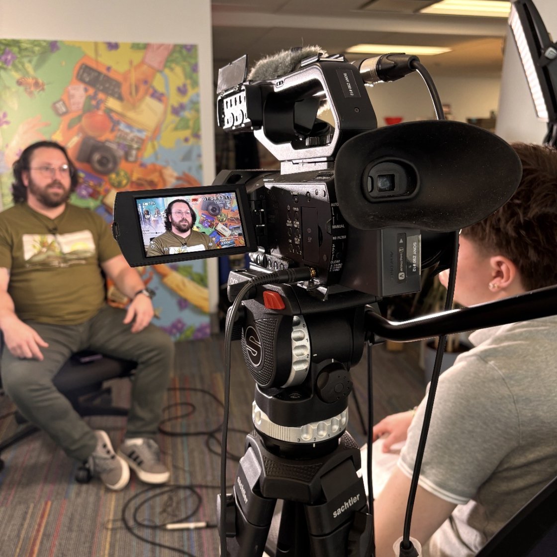 Student interviewing subject with camera viewfinder in focus.