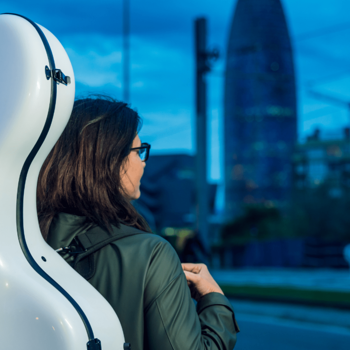 Student with cello on back outside walking at dusk