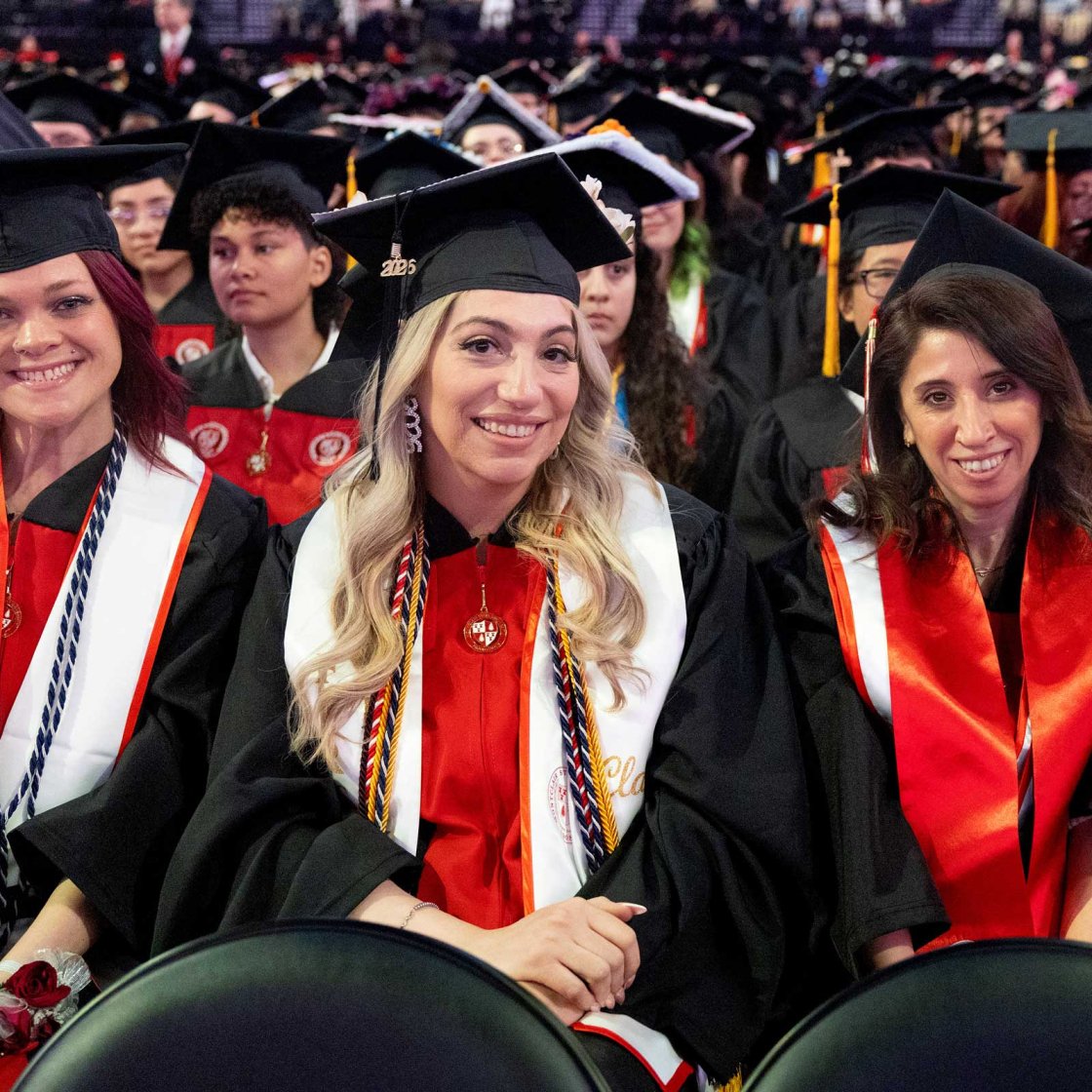 Three women in graduation regalia at Montclair State University commencement.