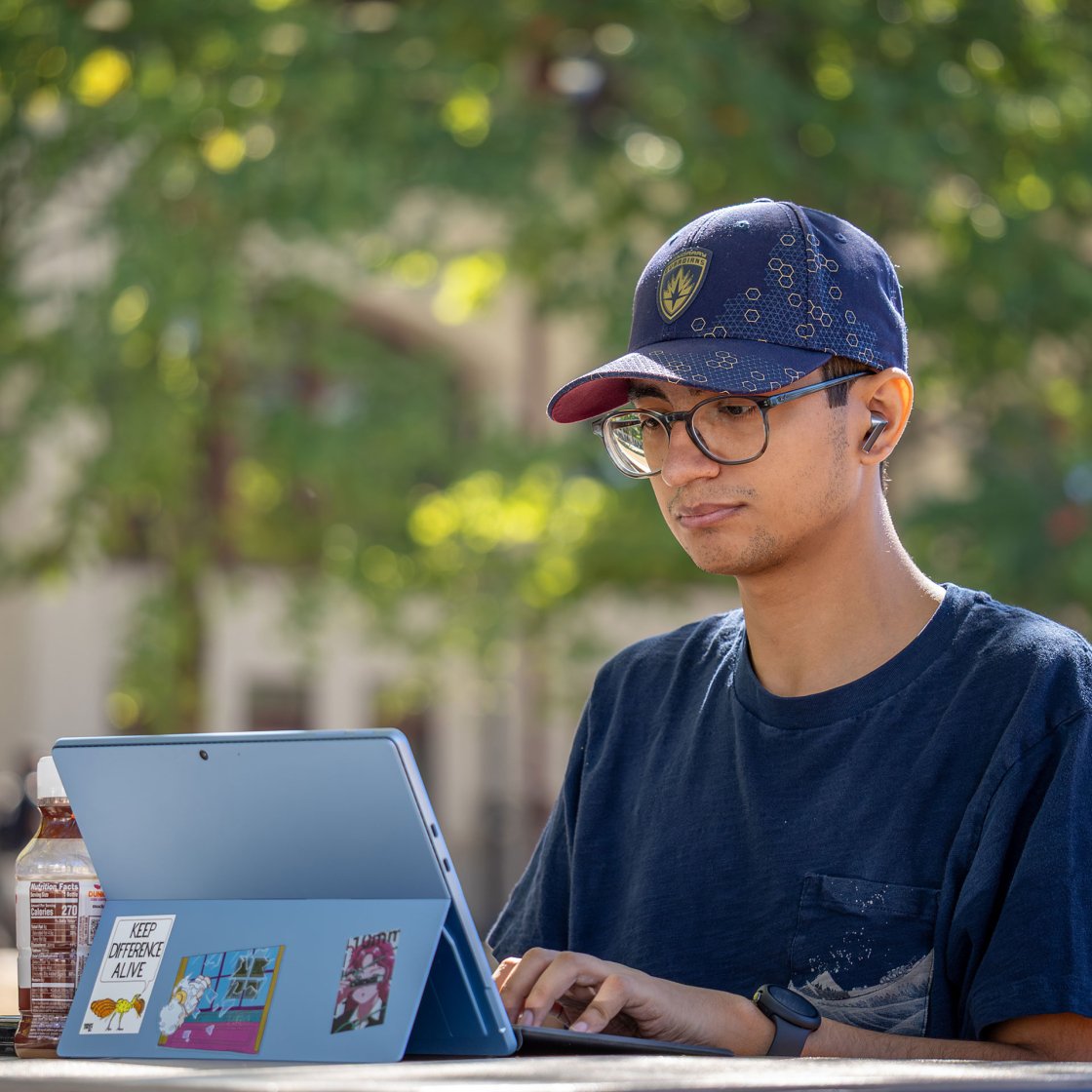 Student working on their tablet outside on campus.