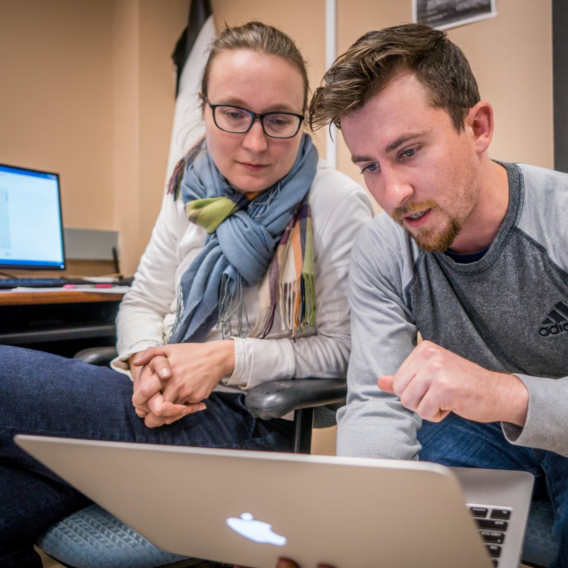 A man and a woman look at a laptop together.