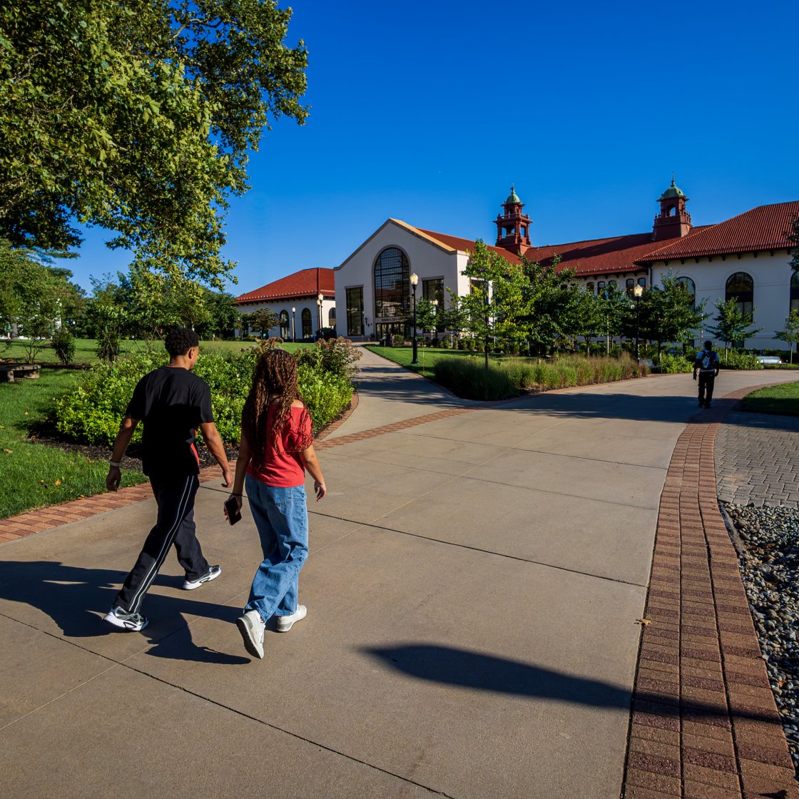 Students walk on campus toward Cole Hall