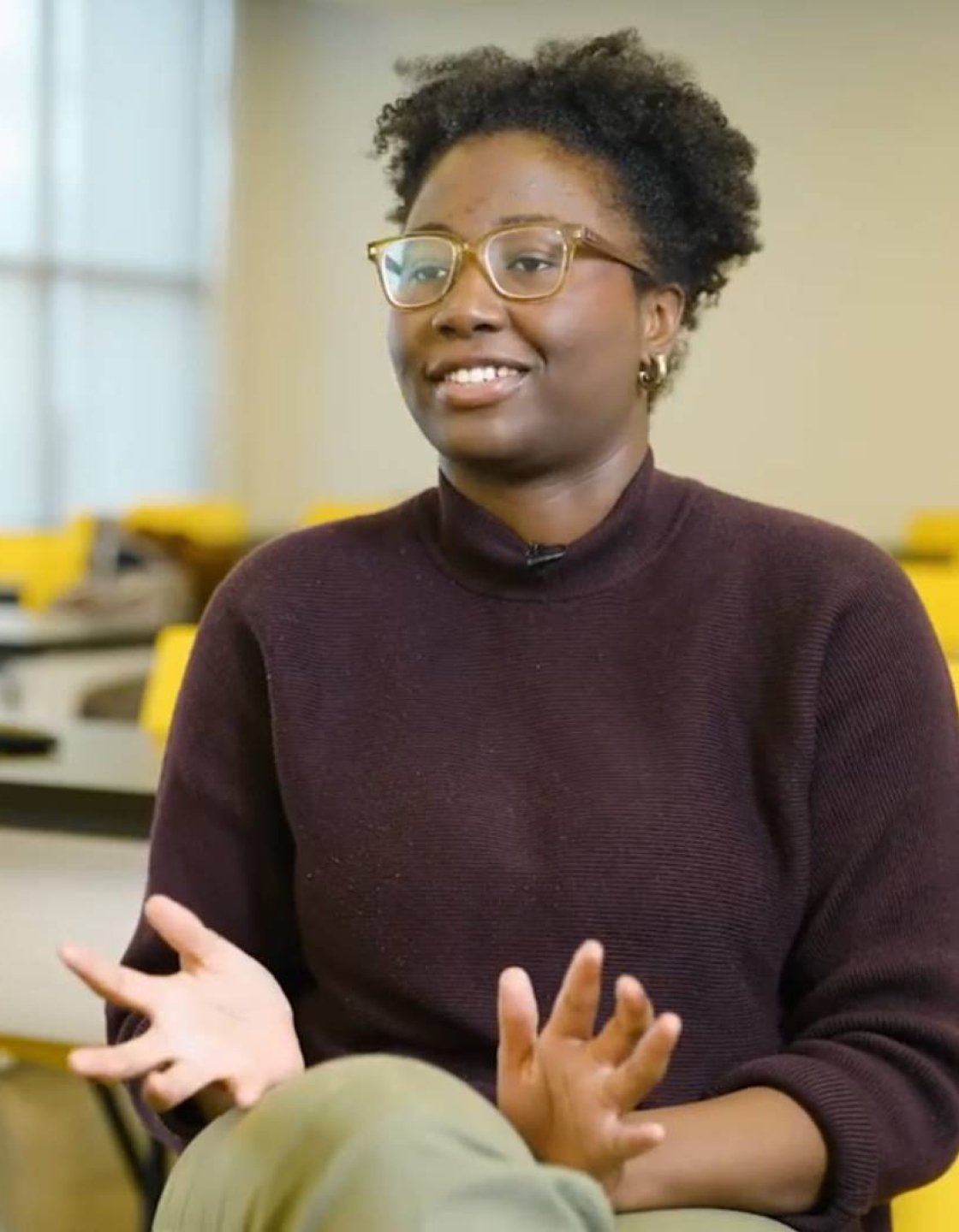 A college student sits inside an empty classroom for an interview