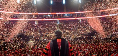 President Koppell addresses graduates from stage as celebratory confetti is shot into the air