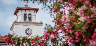 University Hall clock tower with spring blossoms in front