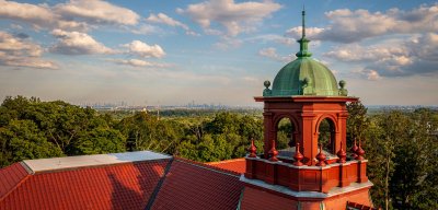 ariel view of the red rooftop and green dome of Cole Hall building with NYC in skyline