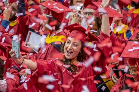 graduate holds cell phone to take selfie amid a flurry of confetti