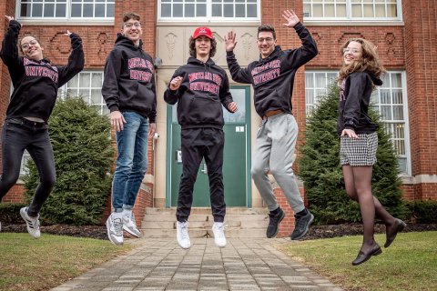 The Povolo quintuplets wear Montclair State University shirts and jump for joy for scholarship offers outside of Passaic Valley High School
