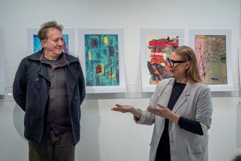 Thomas Mueller and Jennifer Wroblewsk stand before student artwork.