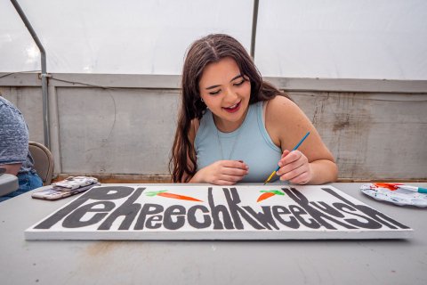 Female student paints sign.