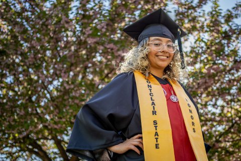 Student Mariana Luna-Martinez in graduation cap and gown with a gold honors stole.