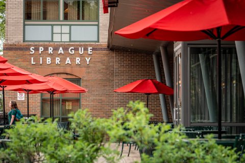 sprague library entrance with tables and umbrellas