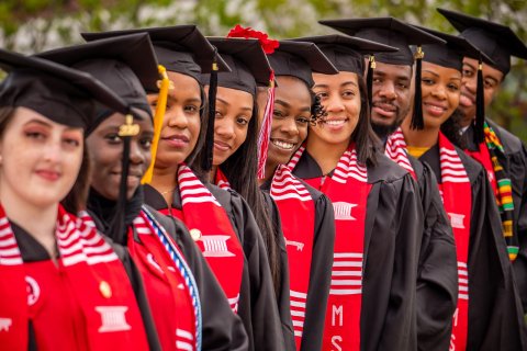 foreshortened view of a line of graduates in cap and gown with EOF shawl
