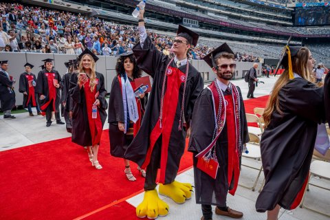 Kyle Cashin at commencement wearing graduation robe and Rocky's feet