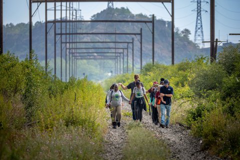 10 people walk on a trail that was once a rail road.