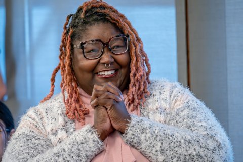 Khara Brown clasps her hands together in an expression of joy and gratitude.