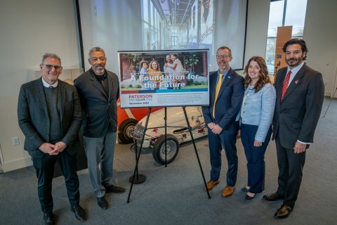 Five people standing with sign in the center promoting One Square Mile initiative