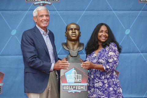 Melanie Mills and Jim Mora Sr. stand next to Sam Mills' head bust