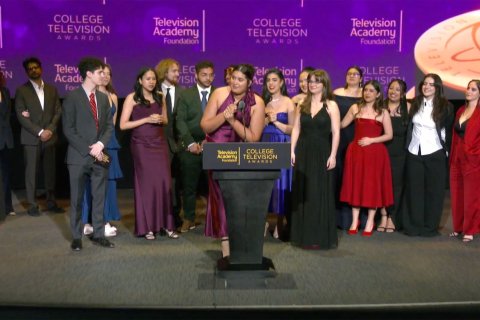Dani Mazariegos, a senior majoring in Journalism and Digital Media, stands on stage accepting the Seymour Bricker Humanitarian Award on behalf of the Arizona Stories team at the 44th College Television Awards in Los Angeles. She is surrounded by 13 fellow student journalists, all dressed in formal evening attire, celebrating their win.