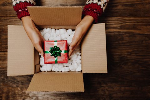 Small gift box being held over a slightly bigger box.