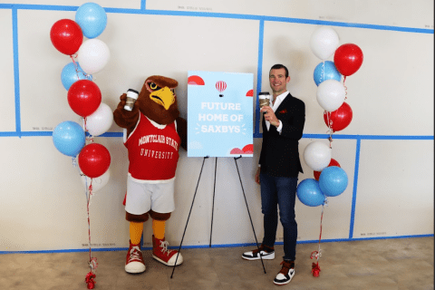 Rocky and a man standing in front of a sign that reads "Future Home of Saxbys"