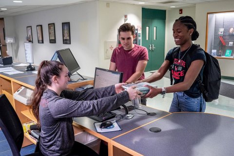 students checking out a book at front desk