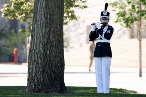 Ashley Mendeke playing flute in military uniform
