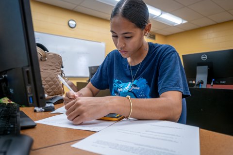 Woman writing in front of computer