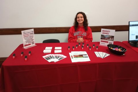student sitting at table with red table cloth and giveaways
