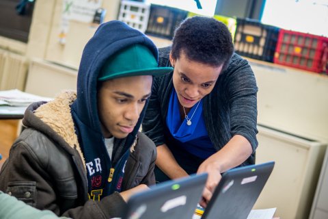 Teacher guiding student on laptop
