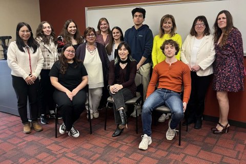 A group of people pose together in front of a whiteboard in a classroom
