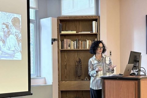 A college professor stands behind a podium and delivers a lecture to an audience