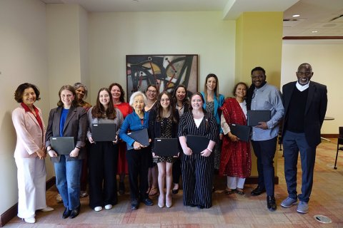 A group of college students and faculty pose together, the students are holding certificates