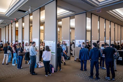 A ballroom crowded with college students presenting projects to judges