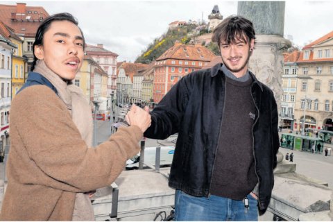 Two college students shaking hands in a town square in Austria