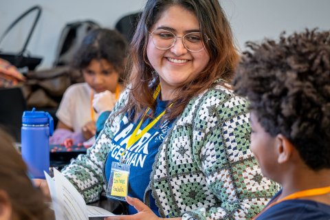 Female os smiling talking to a child with glasses on.