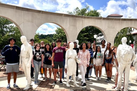 A group of people pose outdoors with an art installation