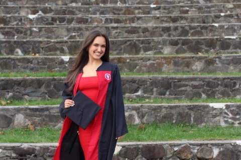 Alum Claudia Challender posing in graduation gown.
