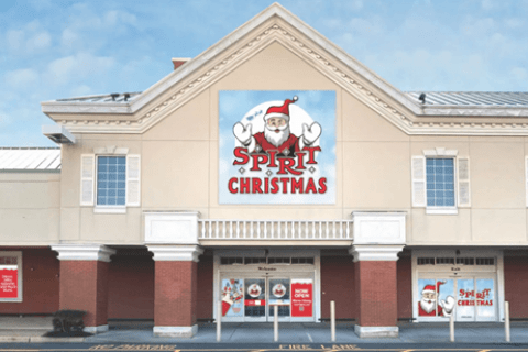 A brown and white two-story building with signs promoting a Christmas store.