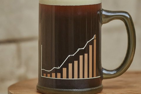A mug of dark beer with foam on top with a line graph on the mug.