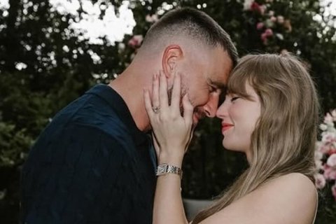 A man and a woman embracing. He is on the left wearing a dark shirt and she is on the right wearing a striped dress.